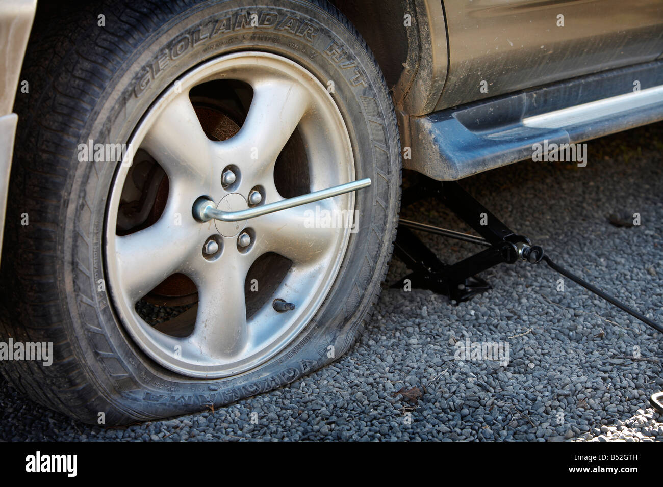 flat tyre on car with wheel brace and jack Stock Photo