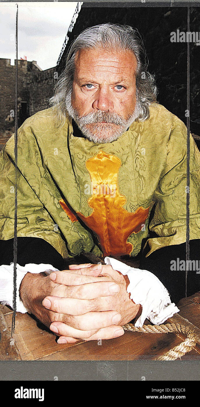 Oliver Reed hands clasped wearing costume as he appears in film