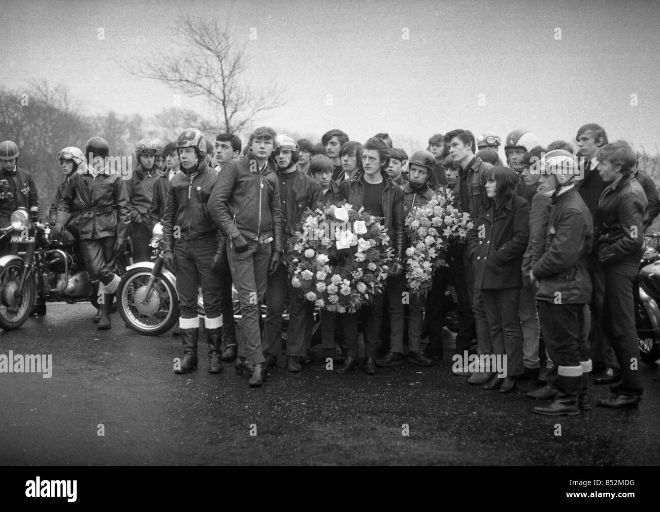 Ton Up Boys Funeral: The mourning dress was black leather. Motorcycles were parked as eighty youngsters solemnly flanked the half mile approach road to  the crematorium, to watch the cortege go by. Then sadly walked behind to the service. The coffee bar set were honouring a promise made with their colleague Michael Munnerley, 18 killed in an accident on his bike. A pact that promised if any of them died the rest would ride to his funeral on their bikes. Our Picture Shows: Motorcyclist seen here before the funeral on their bikes. January 1969 Z1129 Stock Photo