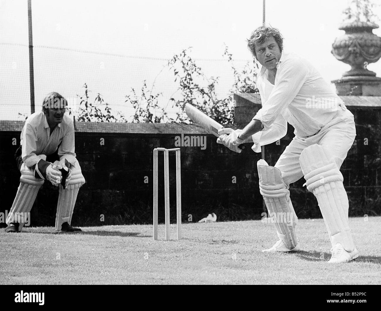 Oliver Reed actor at batting practice for a challenge match in the grounds of his home at Ockley Stock Photo