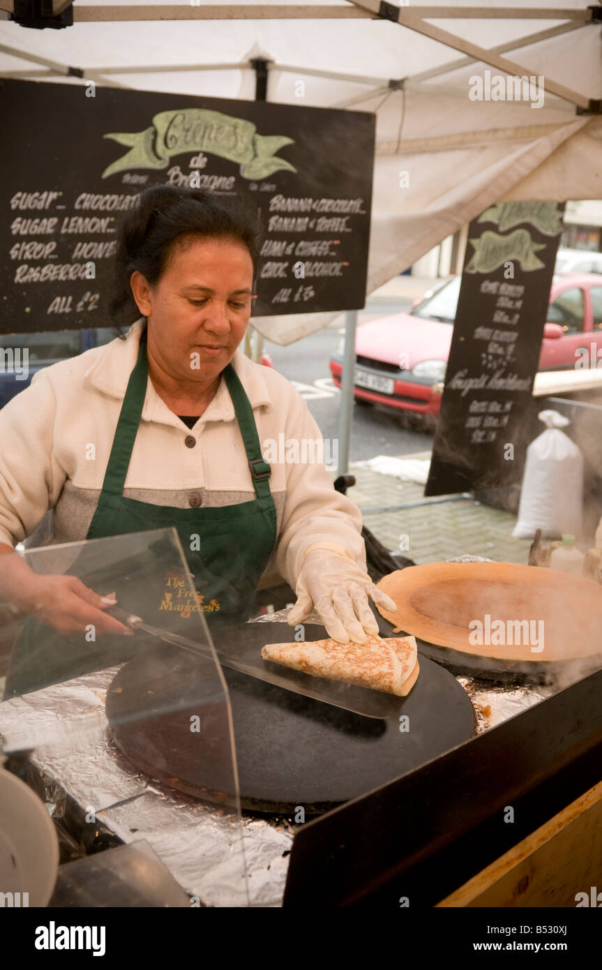 Woman cooking fresh crepes on hotplate at European Food market Aberystwyth Wales UK Stock Photo