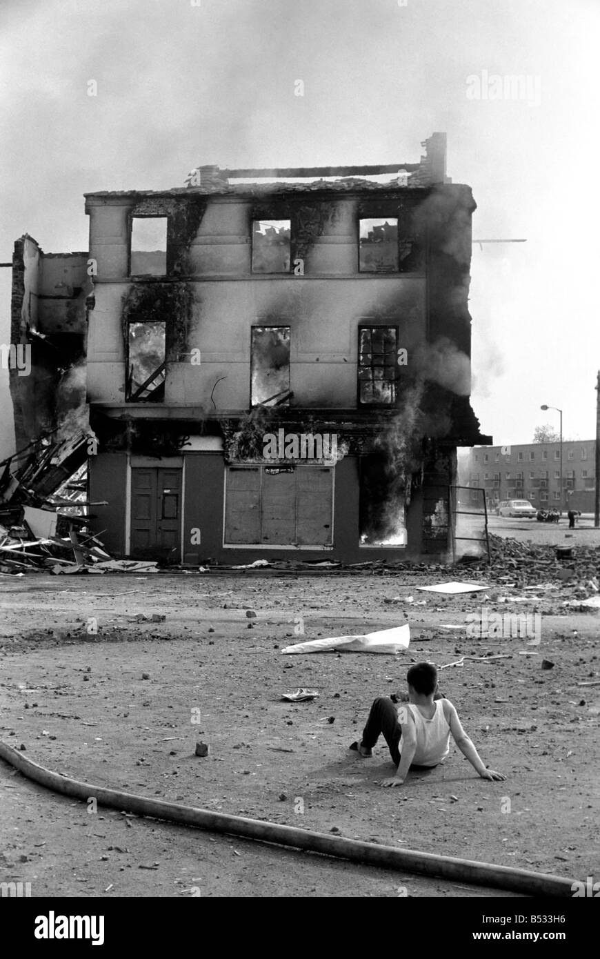 Derry fire in Northern Ireland. For one young boy - a front row seat as just one more building in his city is destroyed. This was the scene at 'aggro' corner in the Bogside as fire destroyed three more shop premises. 24 hours earlier a gelignite bomb had badly damaged the same premises. July 1972 72-7291-001 Stock Photo