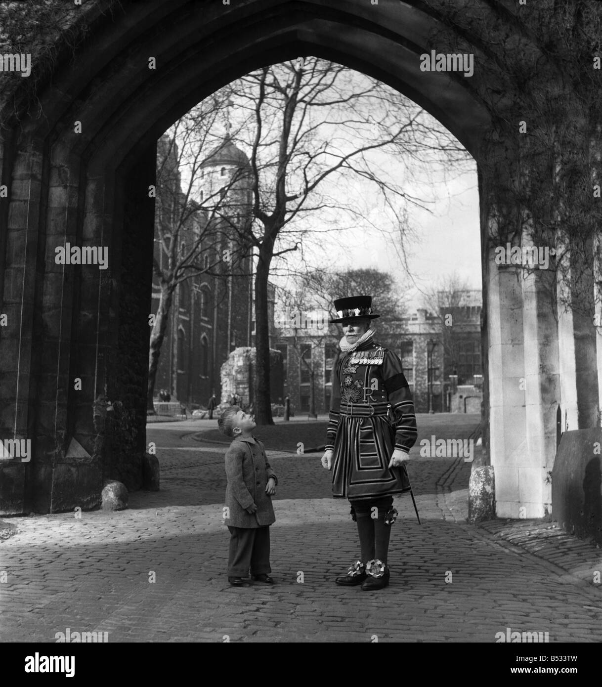 Geoffrey 'Harcup,' aged 4 years with Yeoman Warder David 'Sprake,' 84 Sprake is seen here at the Tower of London. March 1952 Stock Photo