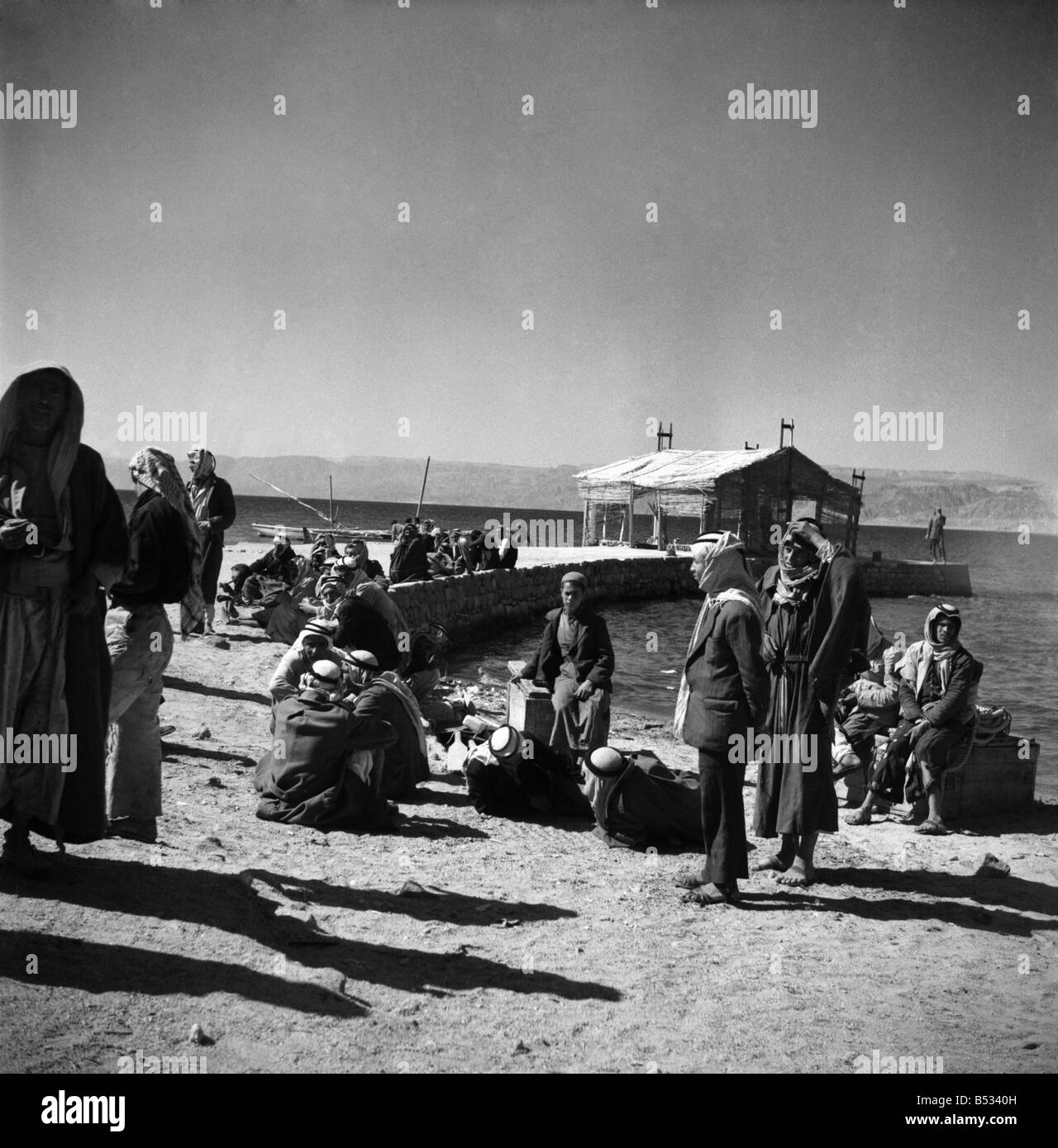 Men waiting by the quay for the ferry to arrive in Aqaba, trans Jordan . March 1952 C1288-003 Stock Photo