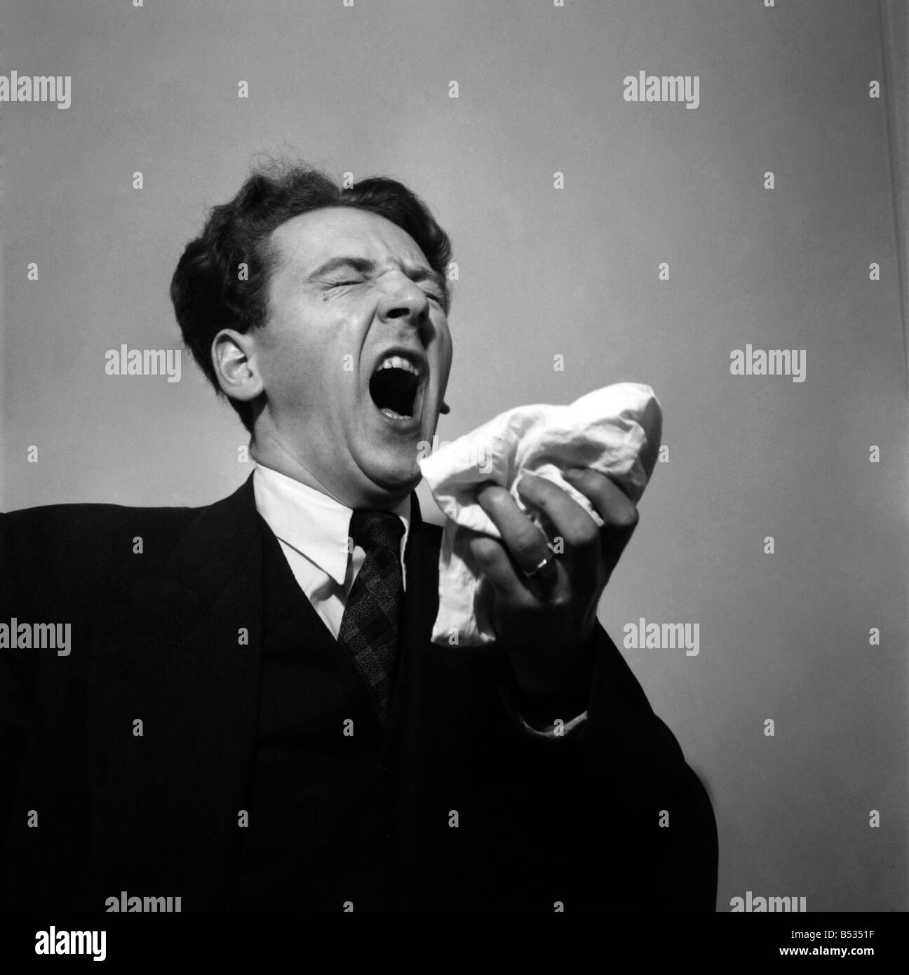 Man holding his handkerchief while sneezing. October 1952 C4925-001 Stock Photo