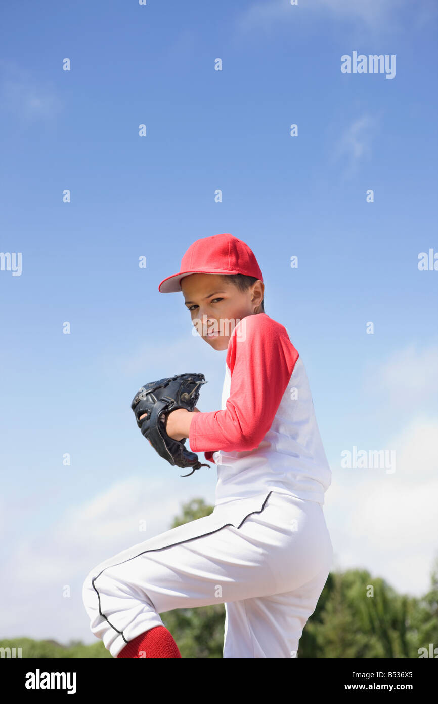 Mixed race boy in baseball uniform pitching in game Stock Photo Alamy