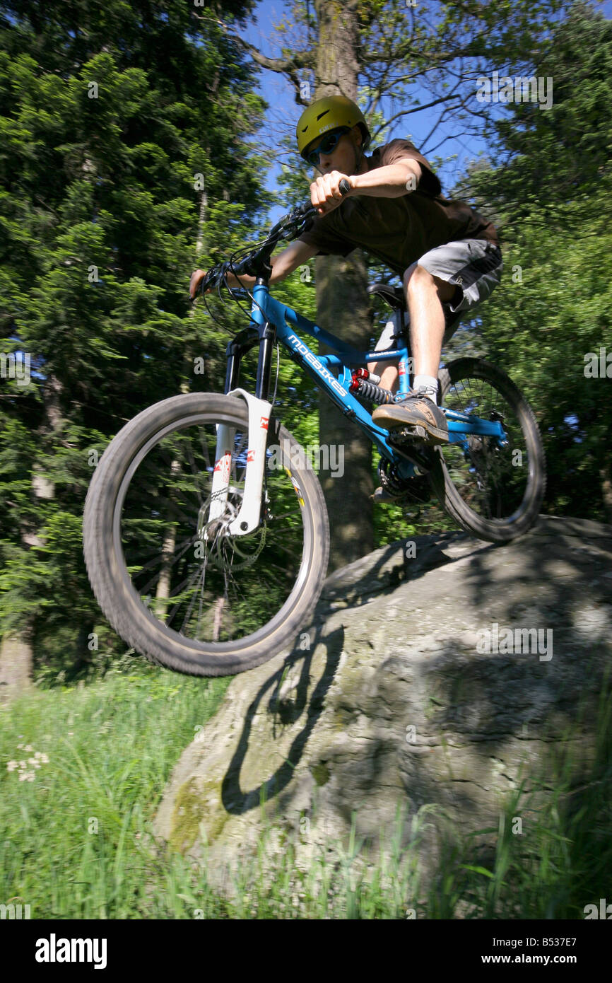 Boy dropping a rock in a park with his freeride mountain bike Stock