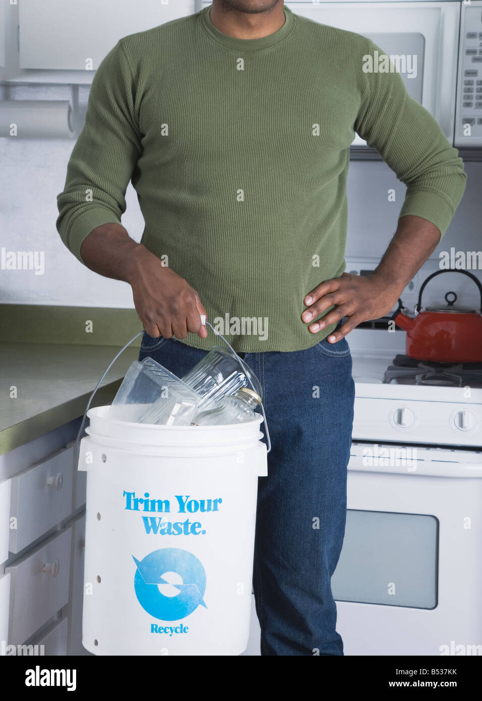 Mixed race man holding recycling bucket in kitchen Stock Photo Alamy