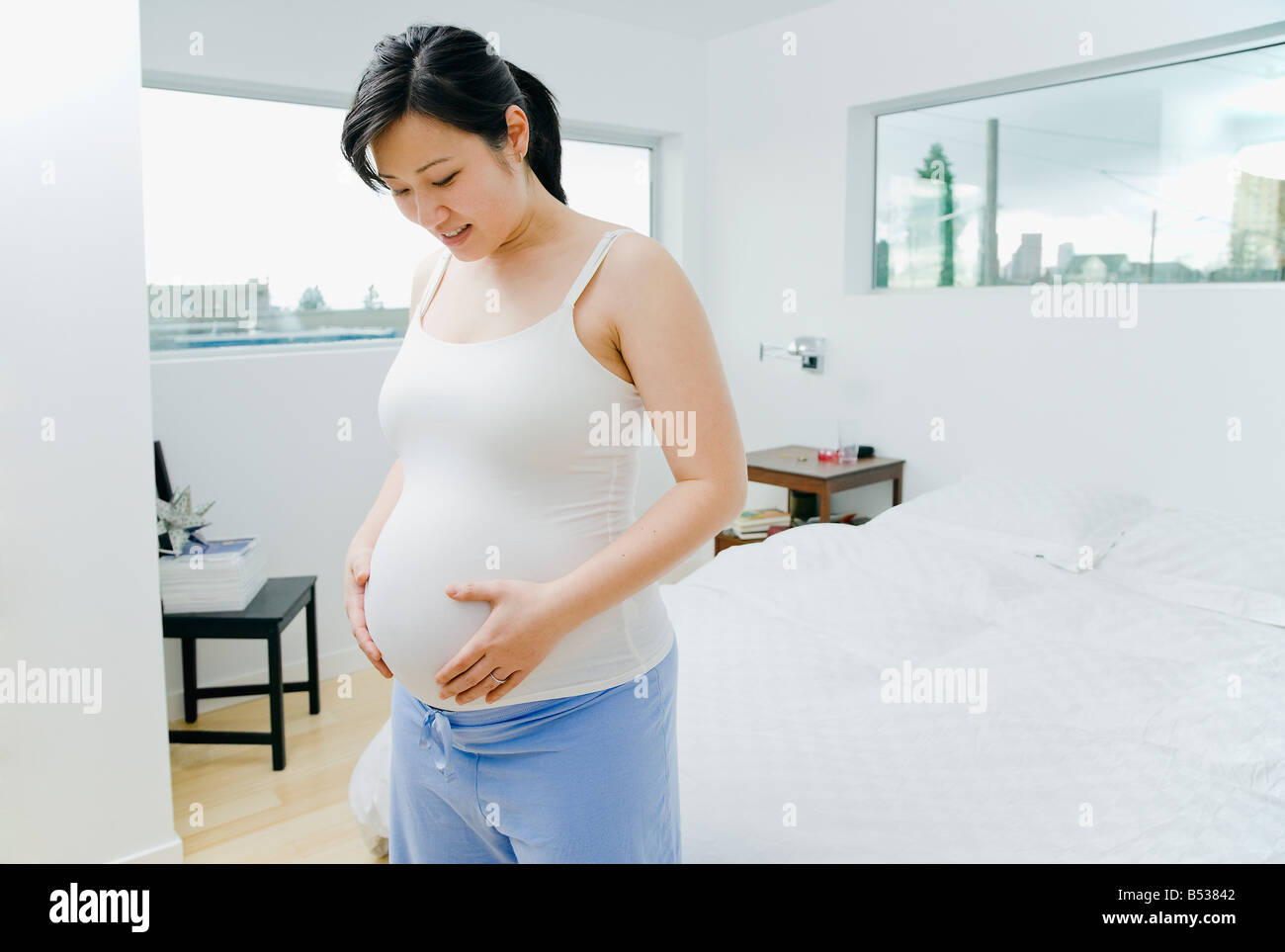 Pregnant Asian woman holding stomach Stock Photo - Alamy