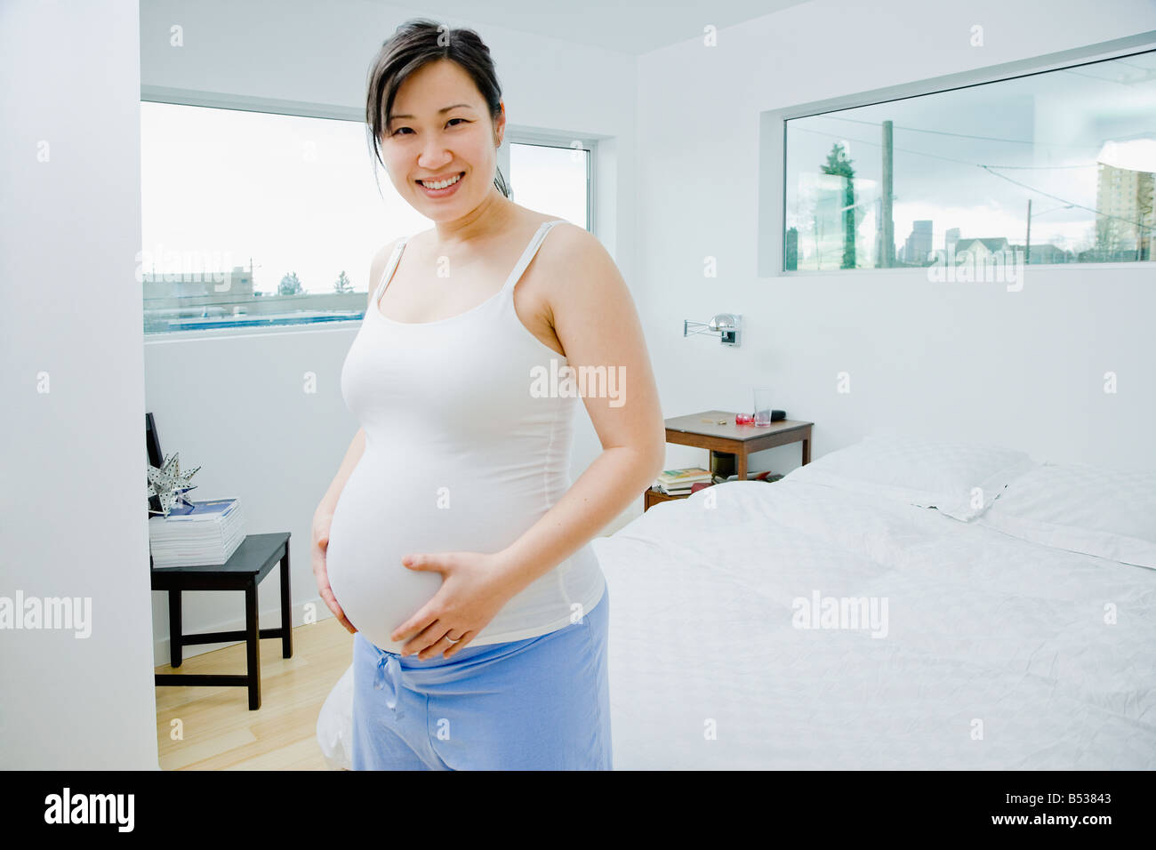 Pregnant Asian woman holding stomach Stock Photo - Alamy