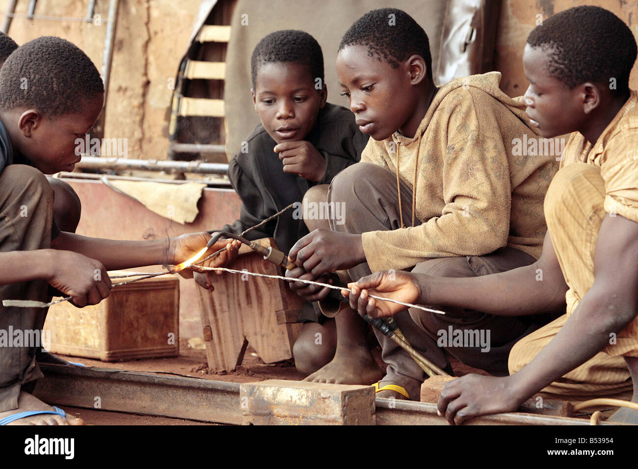 Child Slaves in Benin West Africa February 2007 Child labour working in Benin West Africa young kids working in the forge in Dan Tokpa market Cotouno HIDDEN away in a corner of this foul and sprawling market boys as young as five toil in the festering heat Before you see the faces of these wretched children you hear the sound of their enslavement the clamour of heavy lead hammers on sheets of metal Barefoot and ragged these youngsters were sold for just 10 by their parents to child traffickers who sell them on to work without pay and without hope in demeaning sweatshops Mamoutche a frightened Stock Photo