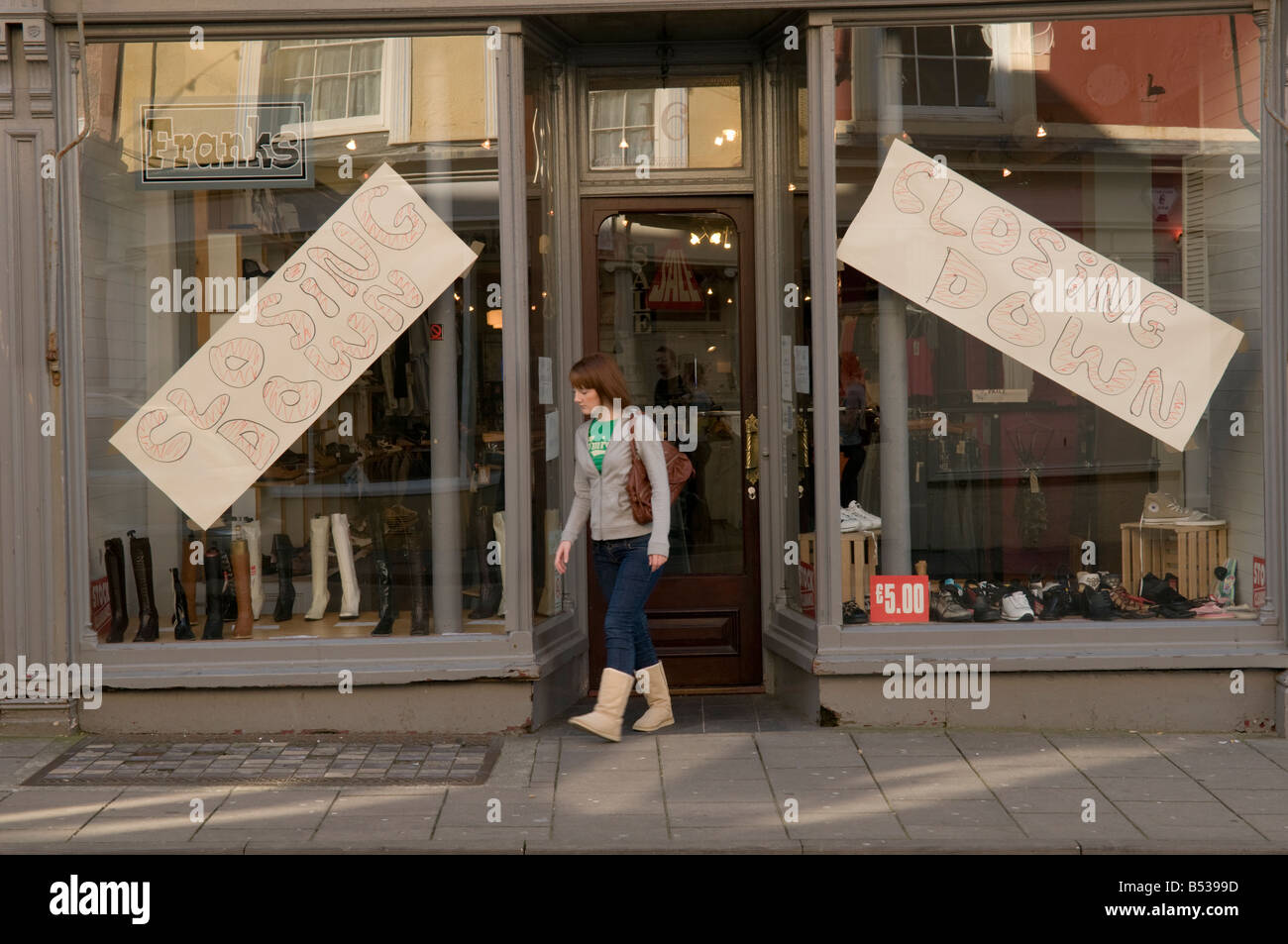 Closing down sale at clothes shop  - woman walking out of the shop door. Stock Photo