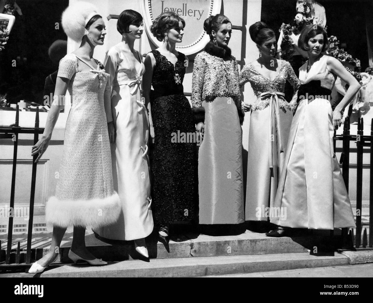 Fashion 1960s.;Women gather in a group on the steps in street. Long ...