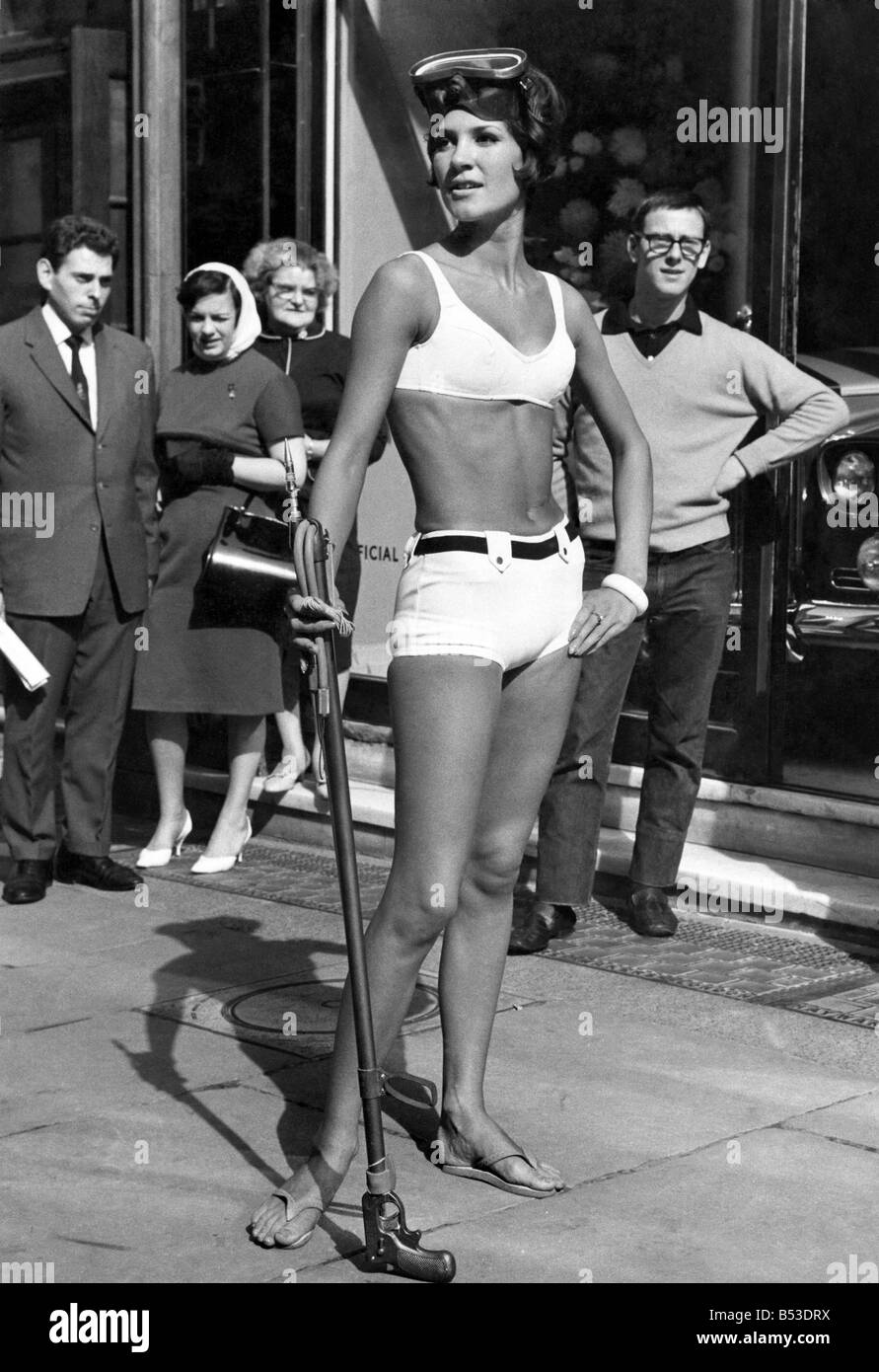 Model Caroline Constance wears her 'James Bond' two-piece of cotton and nylon and carries her underwater spear equipment, watched by lunchtime business man. September 1965 P018010 Stock Photo
