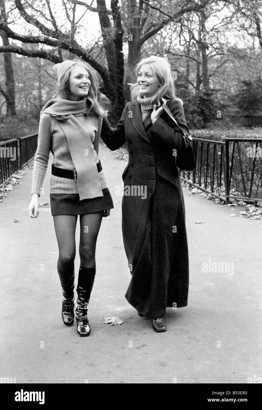 Model Blanche Webb wearing mini skirt and knee high boots with model Monica Hahn wearing a maxi coat as they stroll through the Stock Photo