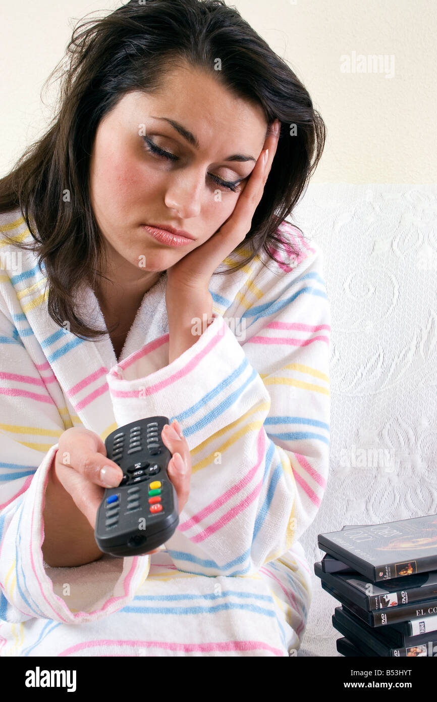 stressed bored young woman with remote in hand channel hopping Stock Photo