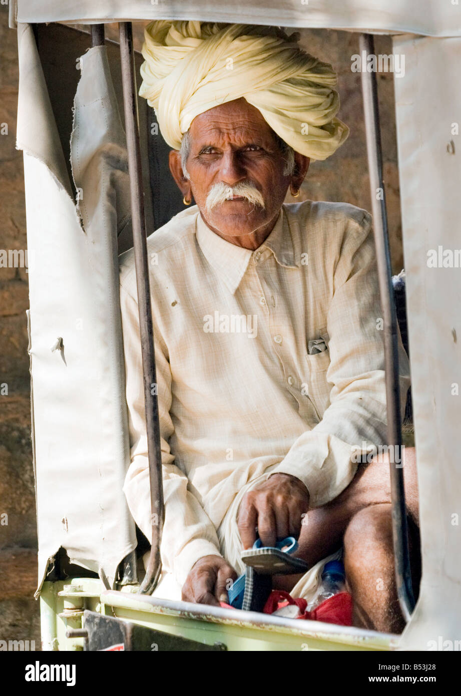 An elderly Indian man in a turban looks out of the back of a jeep, Ranthambore Temple, Rajasthan, India Stock Photo