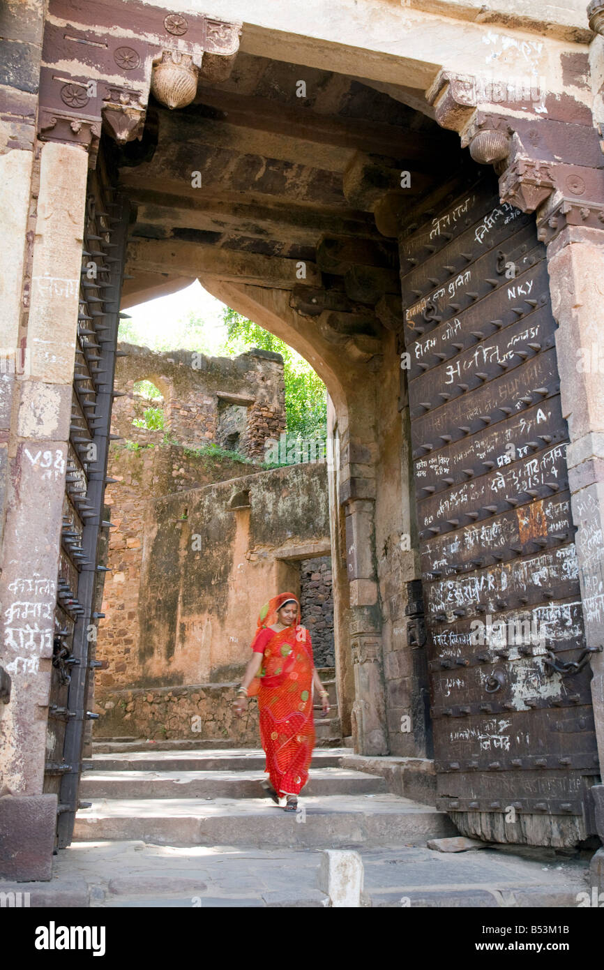 An indian woman in a red sari walks through a gate in Ranthambore fort, Ranthambore National Park, Rajasthan, India Stock Photo