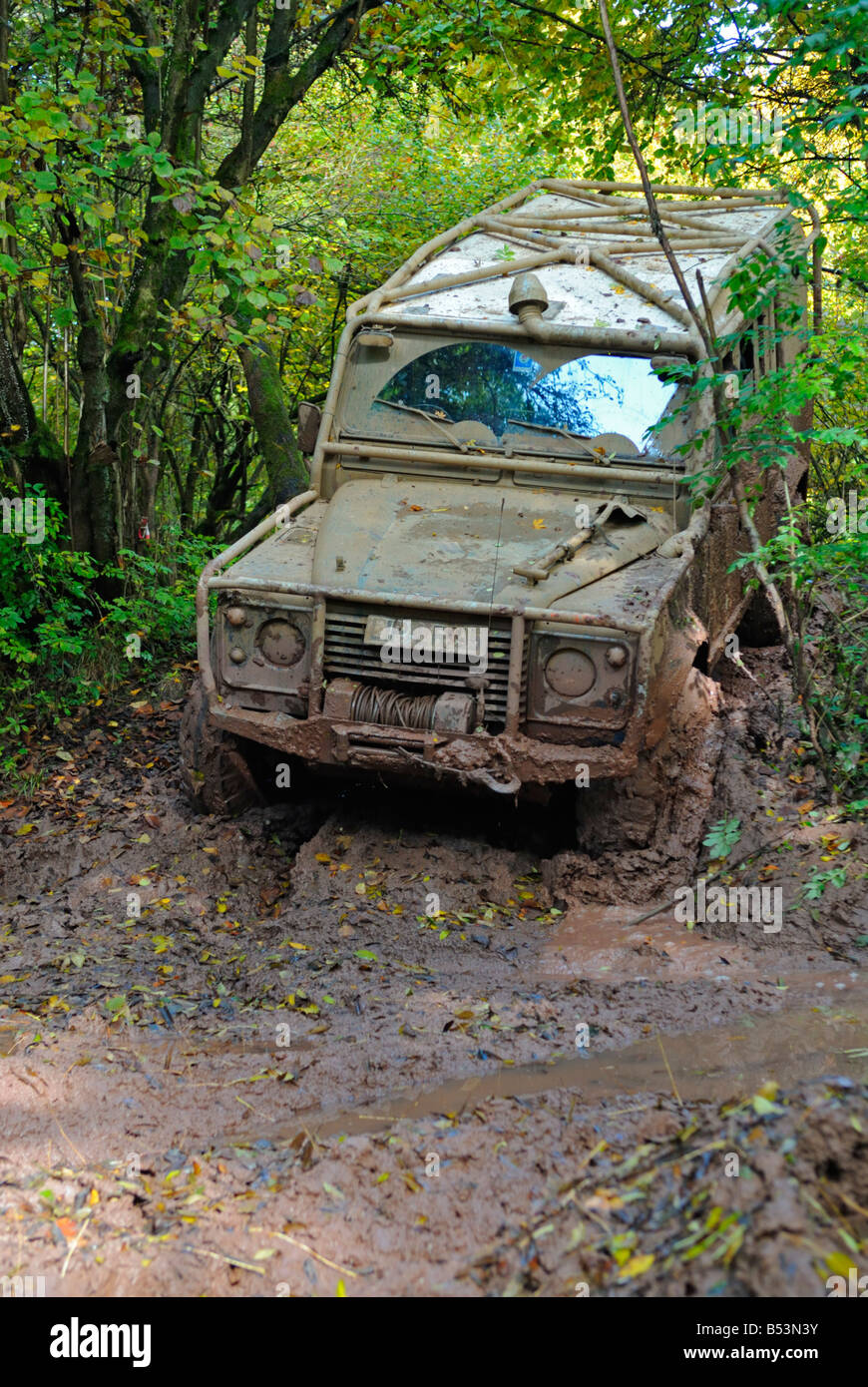Muddy Land Rover Defender 110 going through deep mud on a forest track in the Weserbergland. Stock Photo