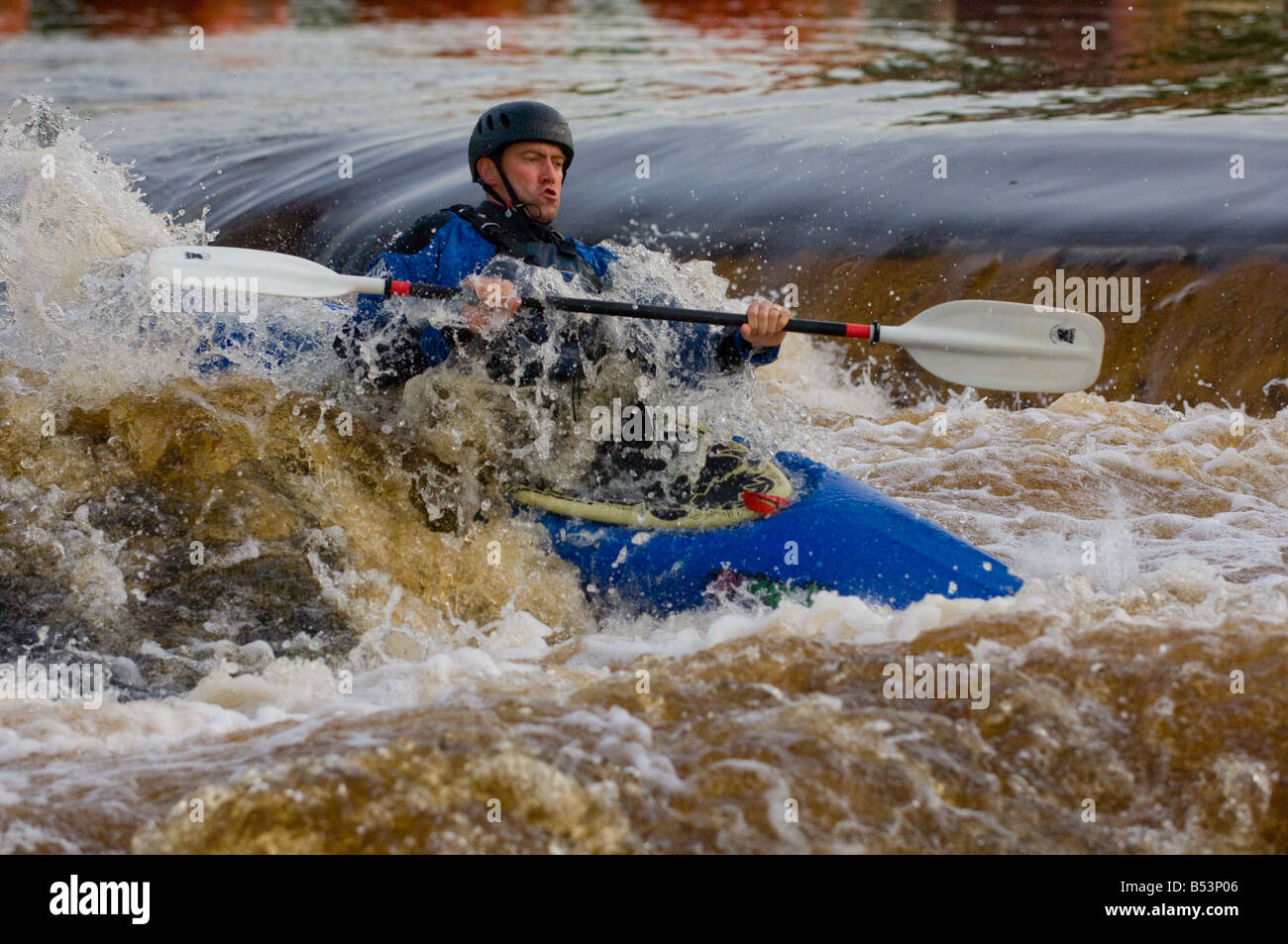 Caucasian male kayaker in a blue kayak in white water. Stock Photo