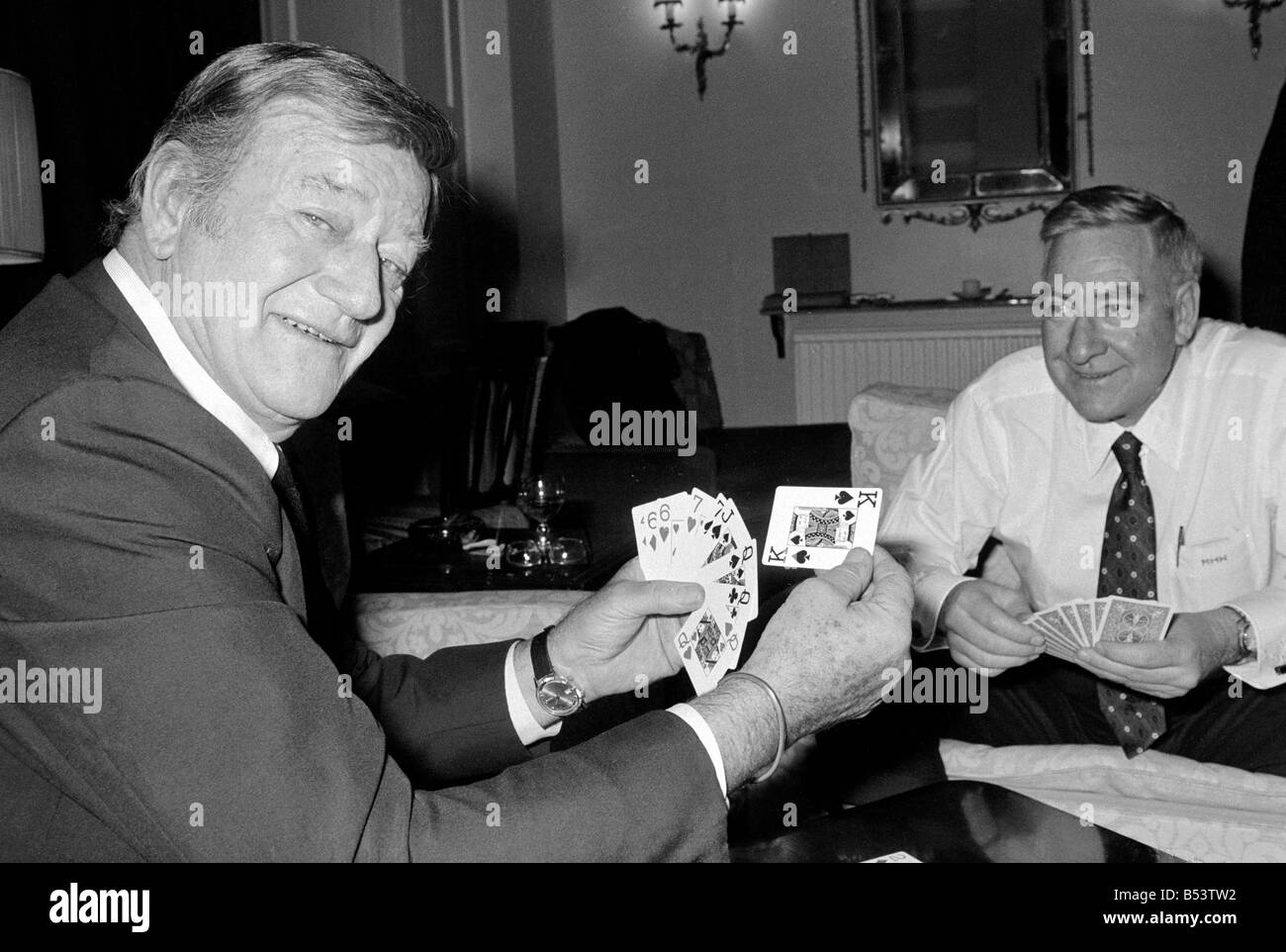 John Wayne pictured relaxing playing cards in his suite at The Connaught Hotel, Mayfair, London. January 1974. Stock Photo