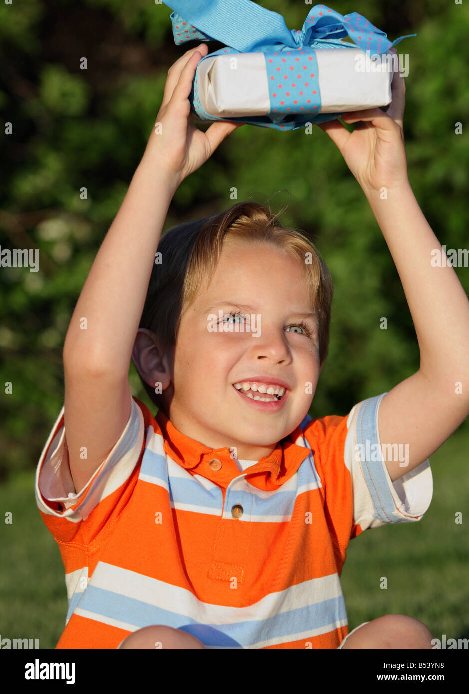 excited little boy holding present above his head Stock Photo