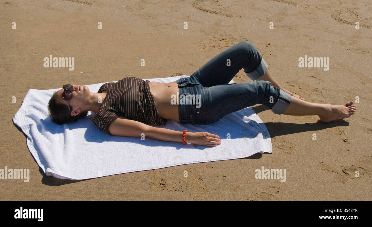 Young woman sun bathing on a towel on the beach, Rhossili Beach, Gower Peninsula, Wales, Great Britain, Europe Stock Photo
