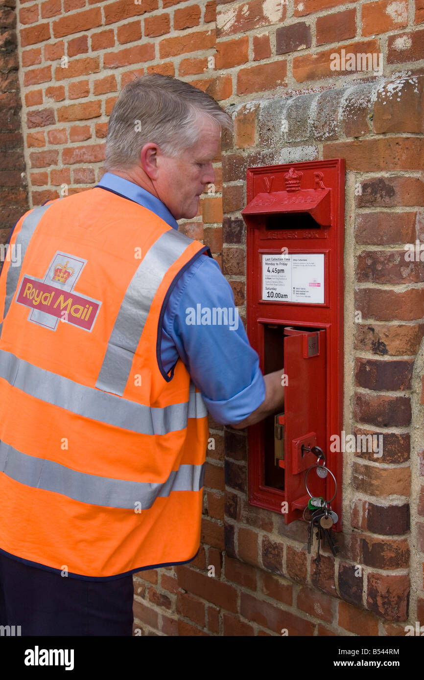 postman working for Royal Mail collecting mail from a postbox Stock Photo