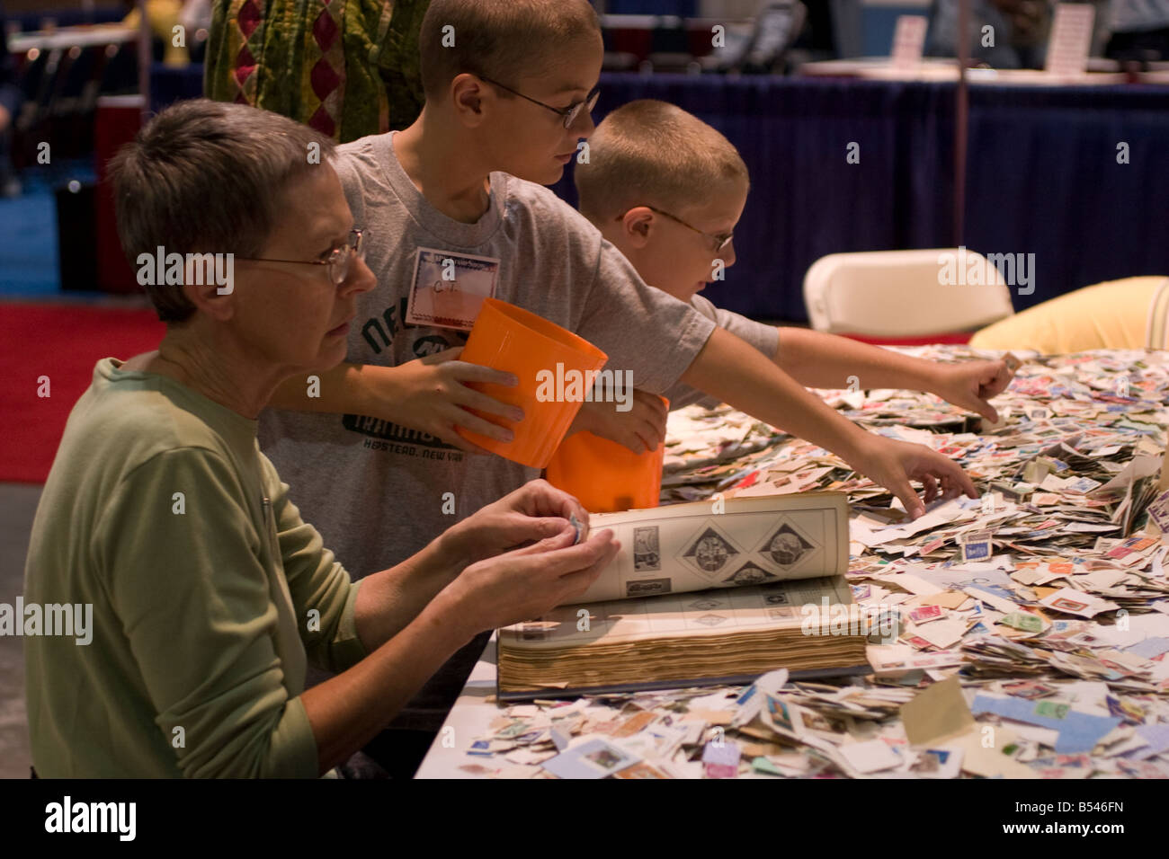 Young and old stamp collectors intently peruses stamps for sale at a bargain booth at the American Philatelic Society stamp show Stock Photo