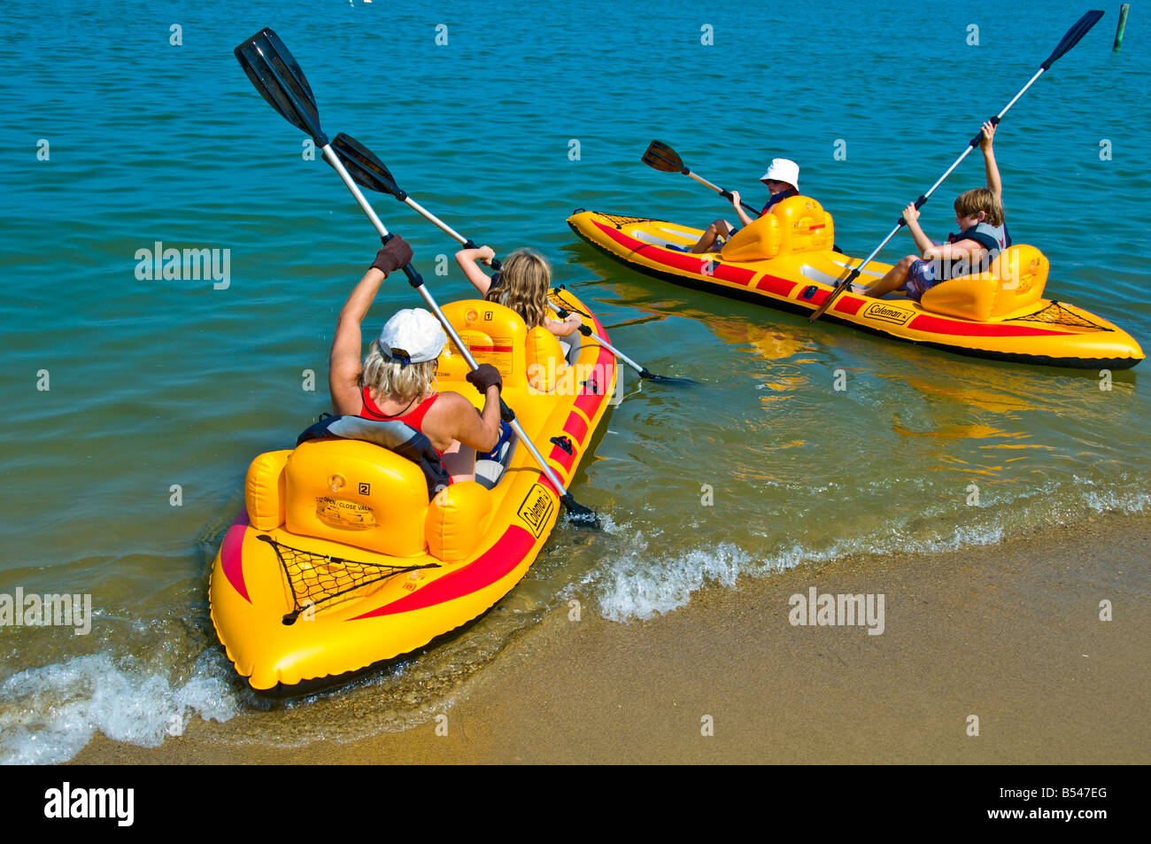 family inflatable PVC yellow kayaks summer vacations shoving off from sand beach Stock Photo