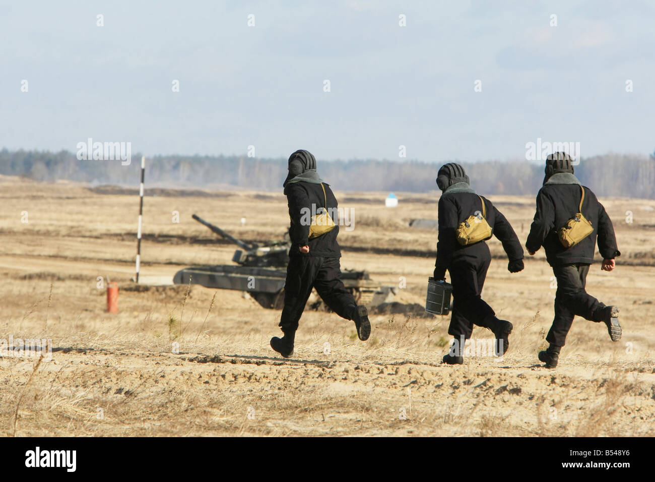three troopers run to a tank Stock Photo