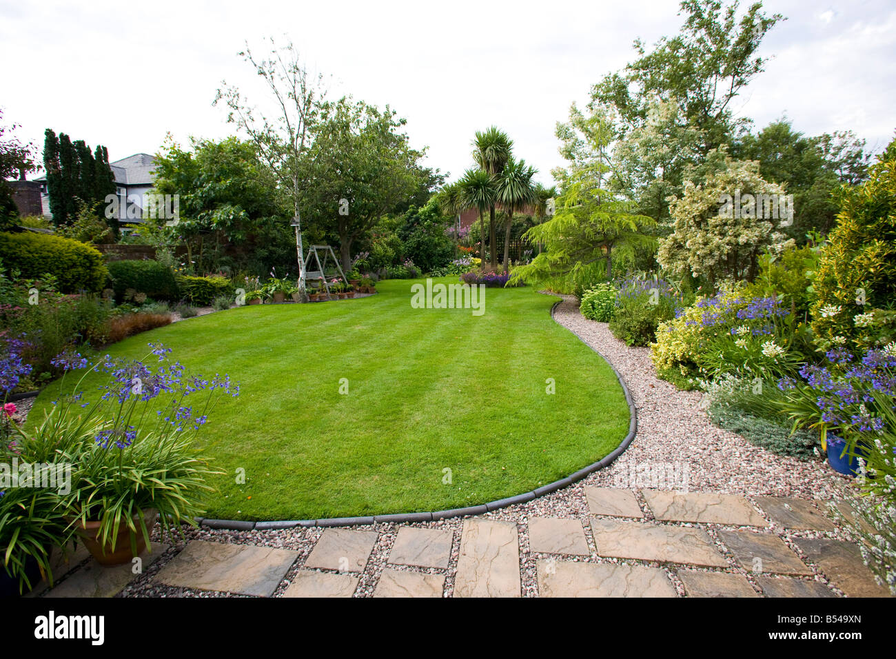 large lawn with curved edge and flagged patio with gravel path Stock Photo