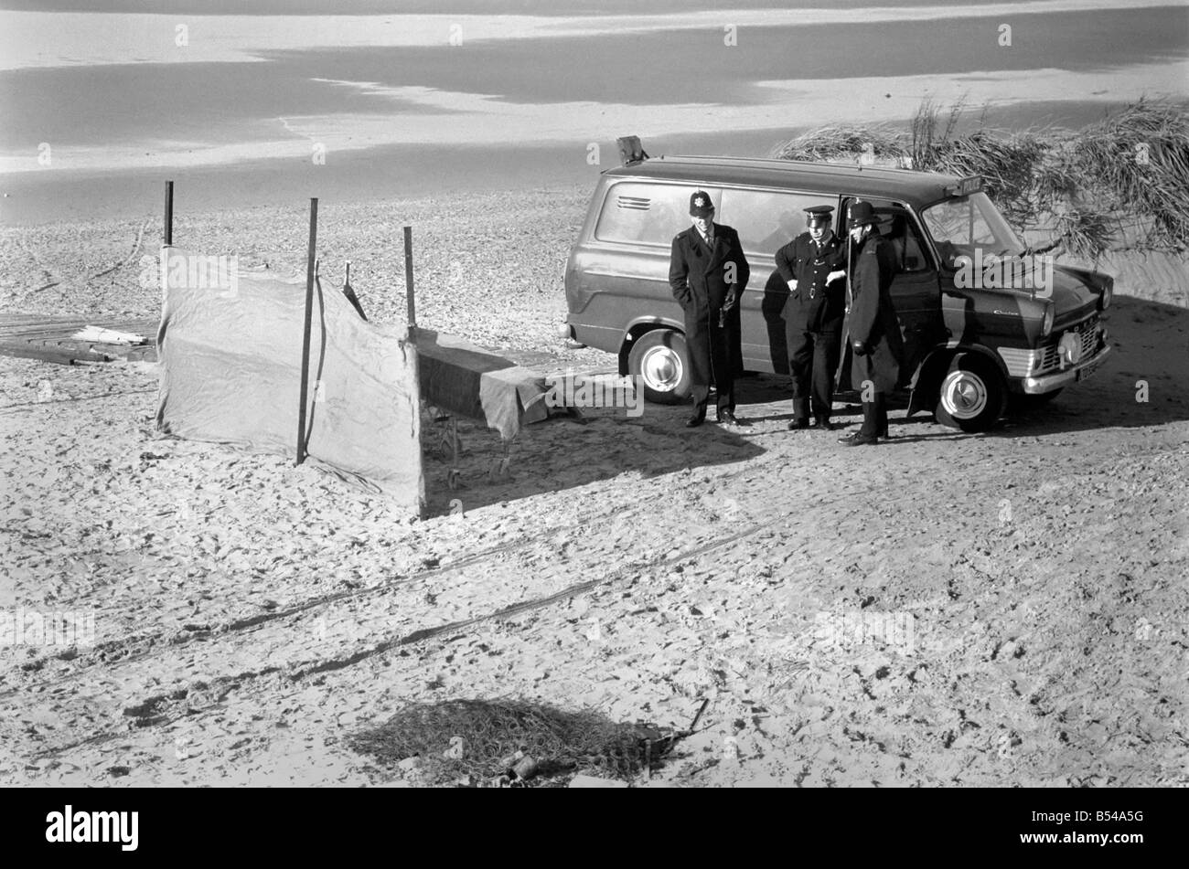 Dead woman found on beach at St. Anness. Scene of the tragedy showing burned out remains of what appears to be a mattress, a coffin behind screens, and a police van at the scene, guarded by policemen. ;November 1969 ;Z10766-007 Stock Photo