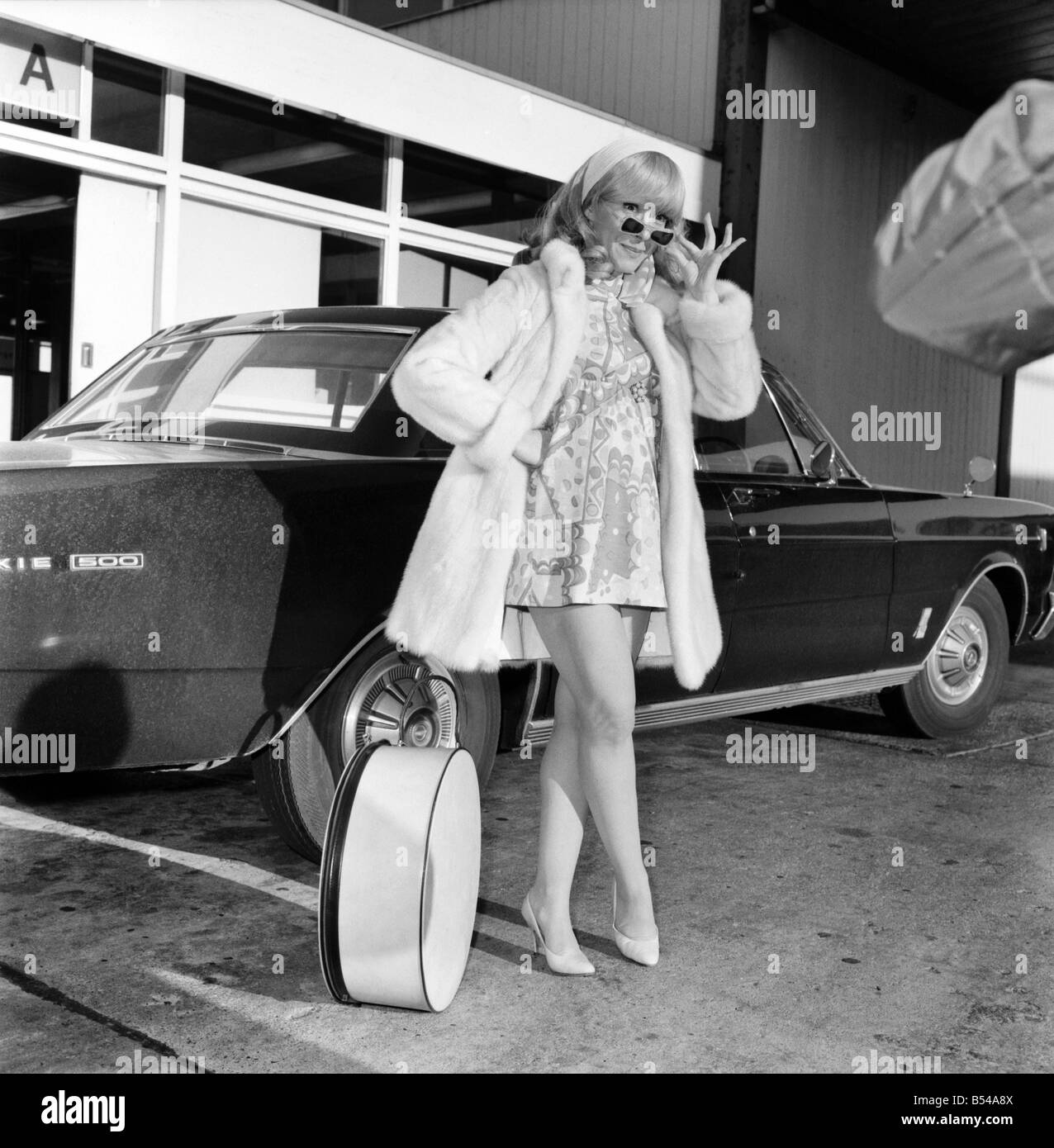 Famous ventriloquist Shari Lewis seen arriving at Heathrow from Los Angeles  for the Royal Variety Show. She wore a white mink minicoat and a  multicoloured mini underneath. She introduced her 'dummy' "Lamb-Chop". ;