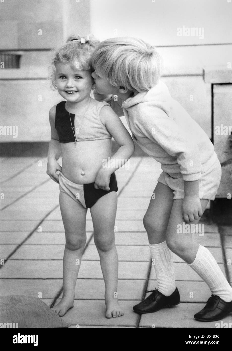 Fashion 1960's: Little Raymond, Finding these fashion models so irresistible. You just can't get away from it. Fashion models seem to be getting younger every day. And more beautiful too. Three-year-old Samantha Gates quite stole the show in her bikini Tuesday (22-10-68) at a London display of children's clothes. She may need a few lessons in deportment. of course. After all, ladies shouldn't be seen pulling up their pants in public. But four-year-old male model Raymond Paul Mears finds her quite irresistible Stock Photo
