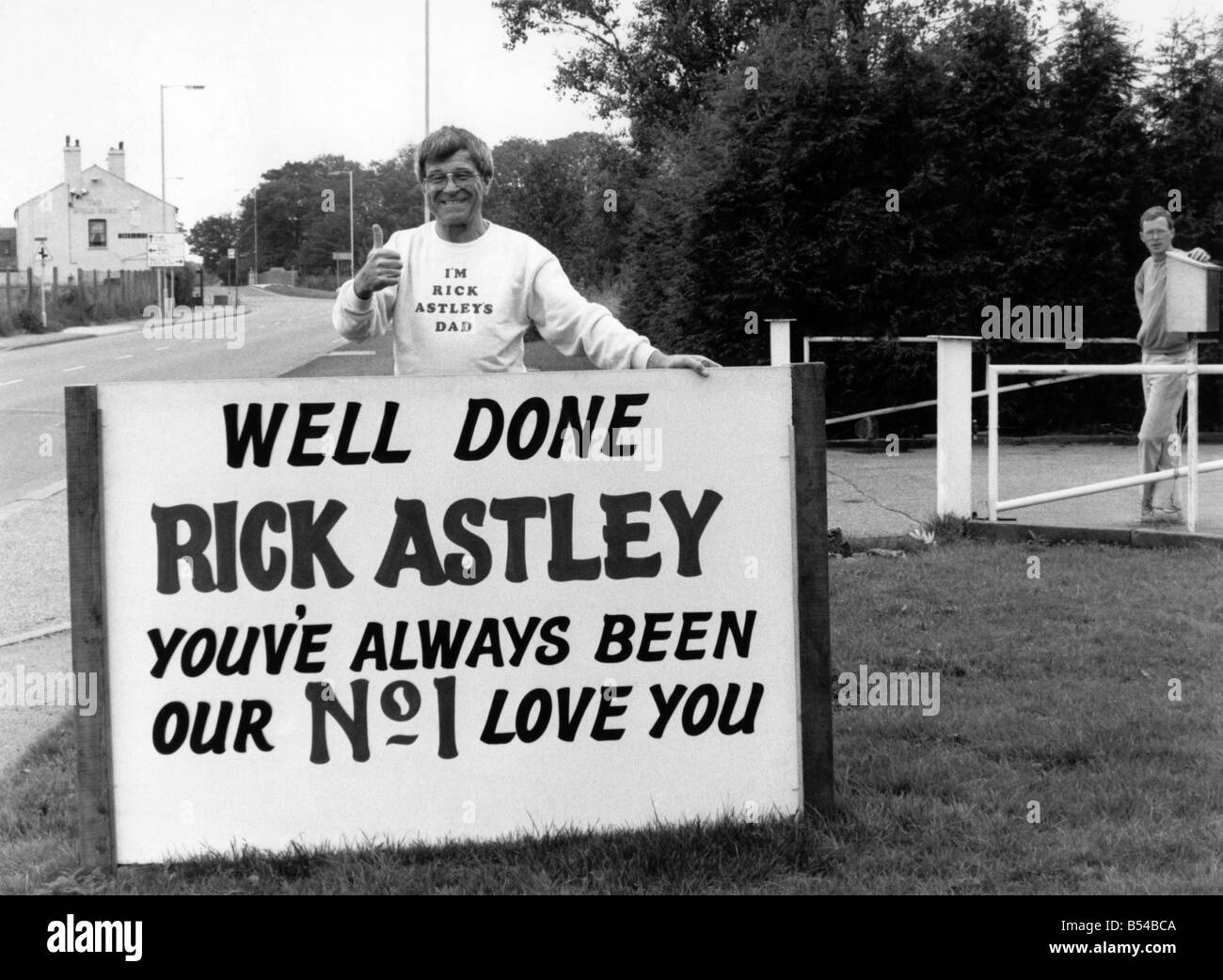 Chart topping singer Rick Astley whose single 'Never Gonna Give You Up' has been at number one in the British charts has got a real fan club in his home town. His father, Ossie Astley, sports a T-shirt with the works, 'I'm Rick Astley's Dad' to show just how proud of his son he is. And his local fans have erected a sign telling Rick how much they think of him. The sign reads, 'Well Done Rick Astley, you've Always Been Our No 1 - Love You.' The 'Well Done' sign for Rick Astley. September 1987 P017185 Stock Photo