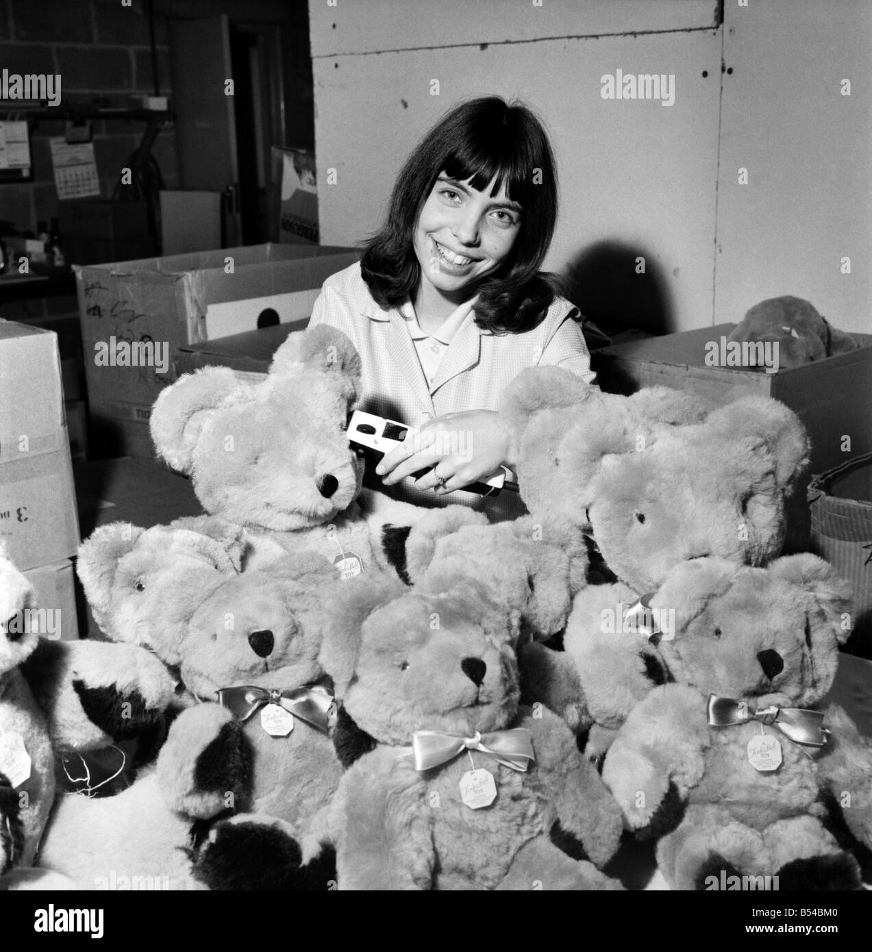 Teenage girl putting the finishing touches to a teddy bear. With her ...