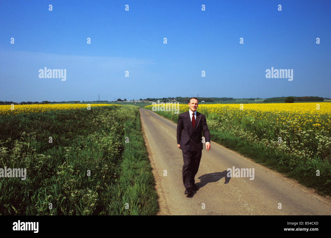 businessman walking down quiet country lane on summers day near Leeds Yorkshire UK Stock Photo