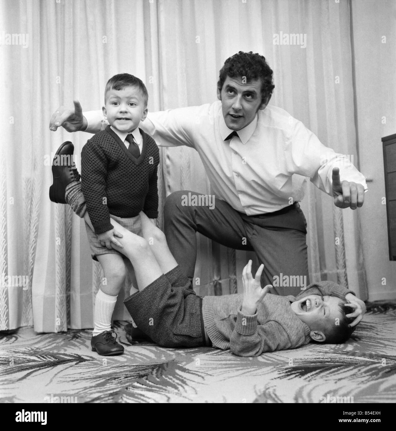Children Humour: The youngest ref of wrestling Brian Dixon, 21, ever to receive a licence of Higher Tranmere, Birkenhead, refereeing a rough and tumble at his sister's home in Bebington between neighbours children Michael Preston, three, and Robert Davies, nine. November 1969 Z10938-002 Stock Photo