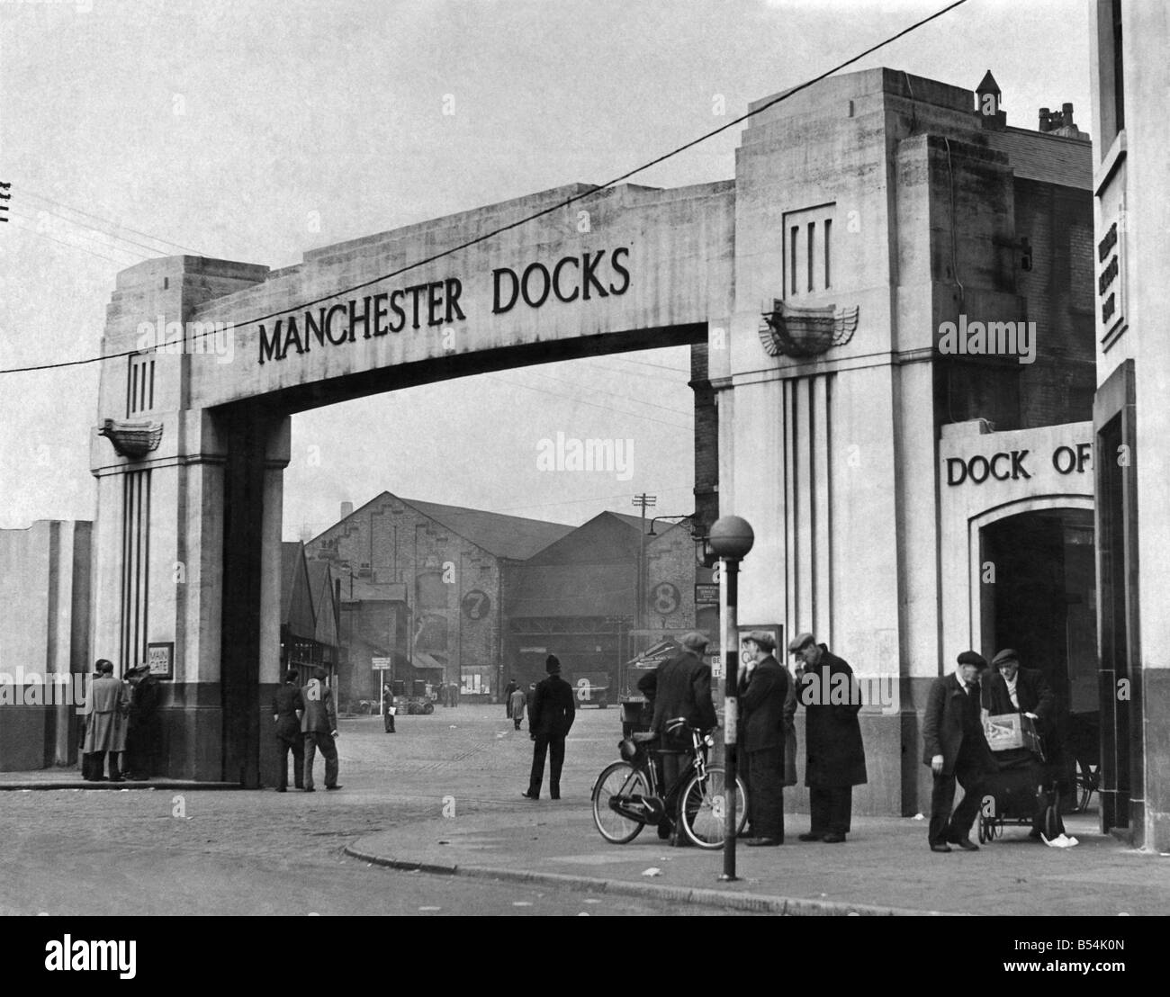 Only a few groups of men stand chatting at the gate of a deserted Manchester dock &#13;&#10;May 1951 &#13;&#10;P011969 Stock Photo