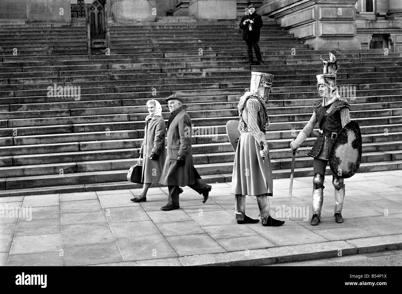Shoppers hurry past the Town Hall steps as a couple of medieval knights are locked in combat in Bolton. The battle was being filmed by the Bolton Octagan Theatre Company. December 1969 Z11749-003 Stock Photo