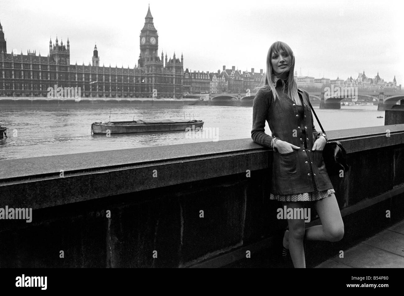 Places , London, England. A woman standing on the bank of the river Thames with the Houses of Parliament behind. November 1969 Stock Photo