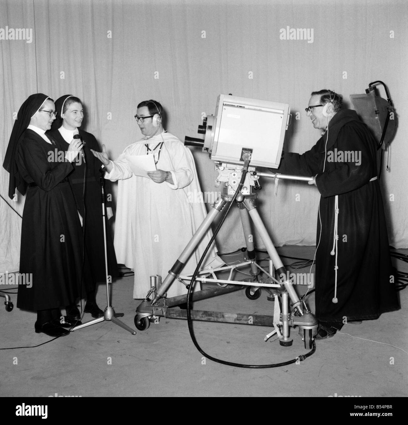 Religion Nuns Humour: The singing sisters from the 'Daughters of Jesus' Convent, Rickmansworth, show they are just as good in front of the television camera as they are behind it. Singing their favorite number 'Dominique', they rounded off a day's utition on the techniques of operating a television camera the new Catholic Television Centre, Hatch End, Middlesex. The singing sisters (left to right) Sister Angela (glasses) and Sister Joan rehearsing a song, directed by the Rev Stock Photo