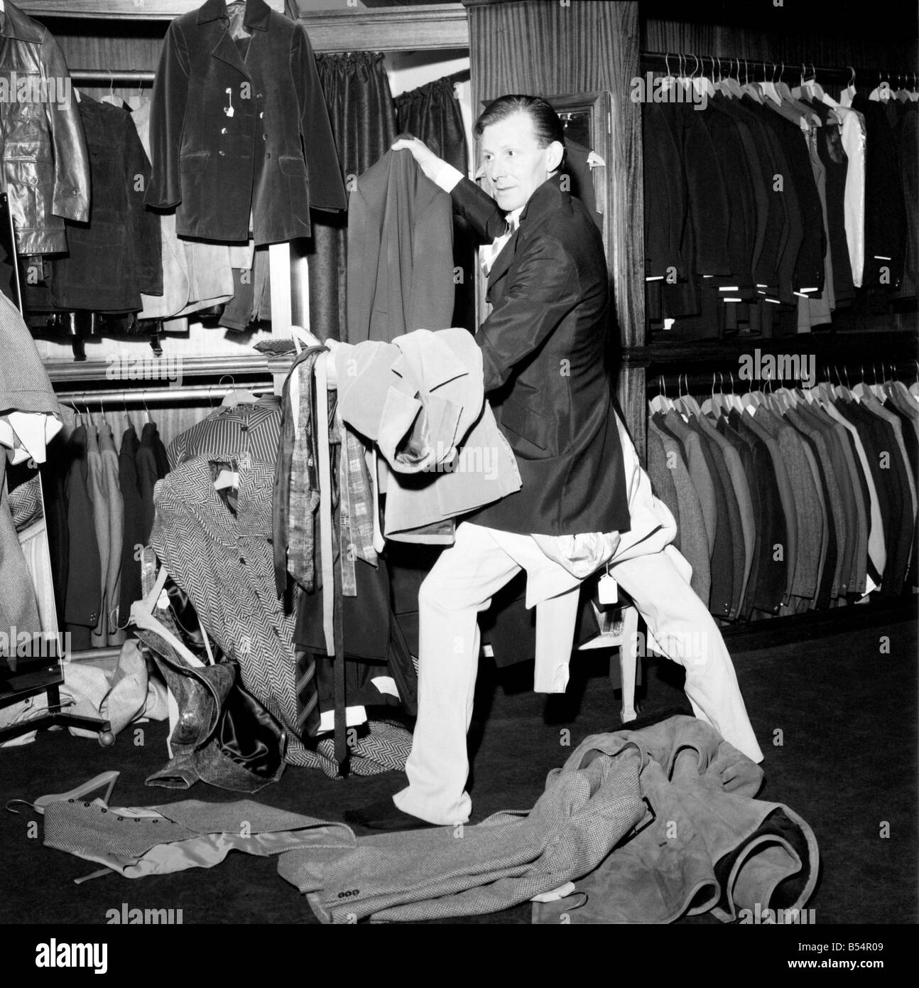 Fashion Clothing Humour. Young male model David Kempton from East Croydon, started work today at the new Young male menswear boutique in Kensington Church Street. His presents there could make the pre-Christmas customers look more than once at him, in fact if they stay long enough they could see him wearing 288 different outfits, for David will be on a marothon clothes change untill Thursday, making six changes an hour, day and night, to set up a new world record for Clothes Changing. David Kempton at the 'Take 6' making a hurried change. December 1969 Z11607-002 Stock Photo