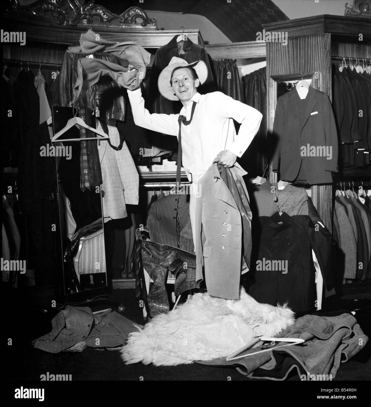 Fashion Clothing Humour. Young male model David Kempton from East Croydon, started work today at the new Young male menswear boutique in Kensington Church Street. His presents there could make the pre-Christmas customers look more than once at him, in fact if they stay long enough they could see him wearing 288 different outfits, for David will be on a marothon clothes change untill Thursday, making six changes an hour, day and night, to set up a new world record for Clothes Changing. David Kempton at the 'Take 6' making a hurried change. December 1969 Z11607-007 Stock Photo