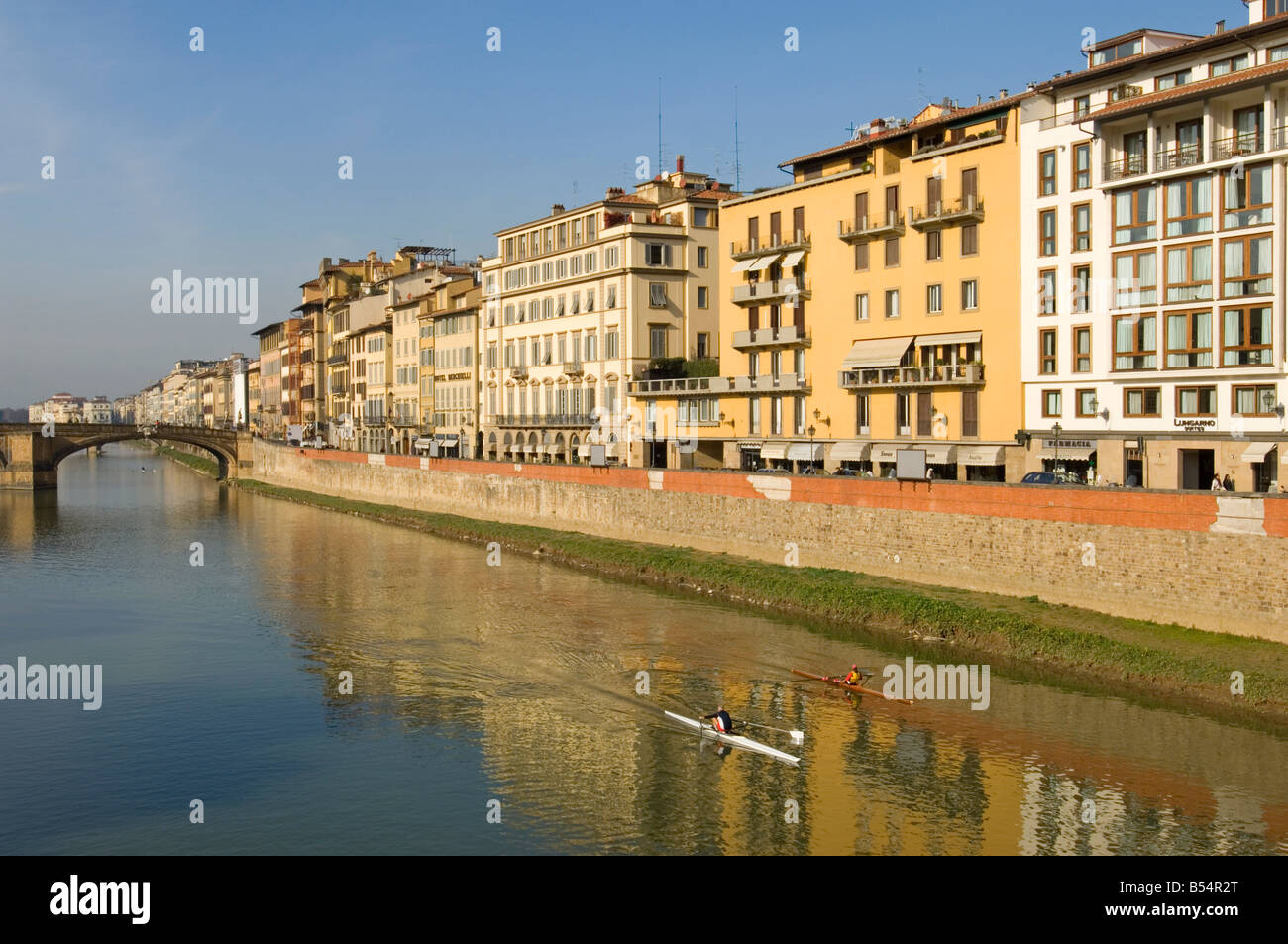 The buildings on Lungarno Degli Acciauoli in Florence reflected in the river Arno with 2 people rowing on the water. Stock Photo
