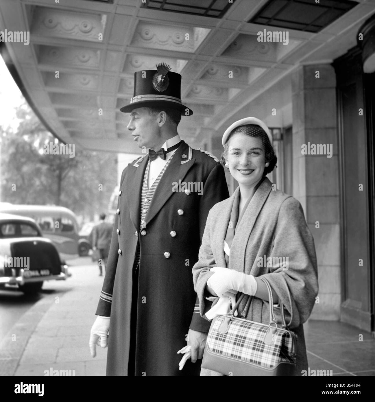 Holidays: Barbara Synder, 23 year old Air Stewardess from Long Island, America, in London for 1 week as winner of an American Competition for 'Girls with Taste'. Miss Snyder has spent one week in Paris and is one of 10 winners of the competition which drew 39,000 entries seen here with the footman of the Dorchester hotel. August 1953 D4084 Stock Photo