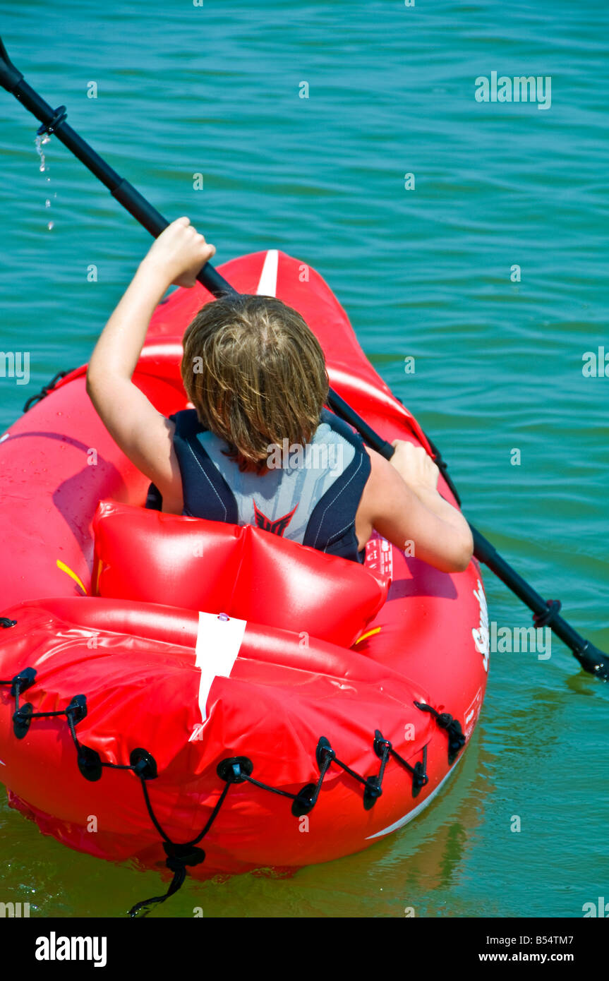boy young teen kayaking bright color red PVC inflatable sit-on-top kayak Stock Photo