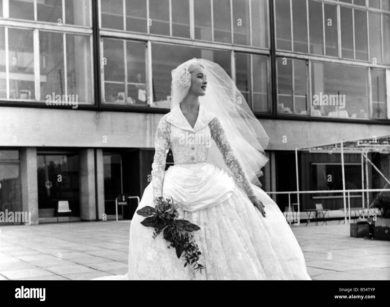 The National Fabric Fair Fashion Parade at The Festival Hall: Jill Howard wears a wedding dress in witchcraft lace of silk and rayon. It has a tight bodice and sleeves and balooning skirt of lace over a polonaise faille. The designer is Victor Stiebel. October 1953 D5963-003 Stock Photo