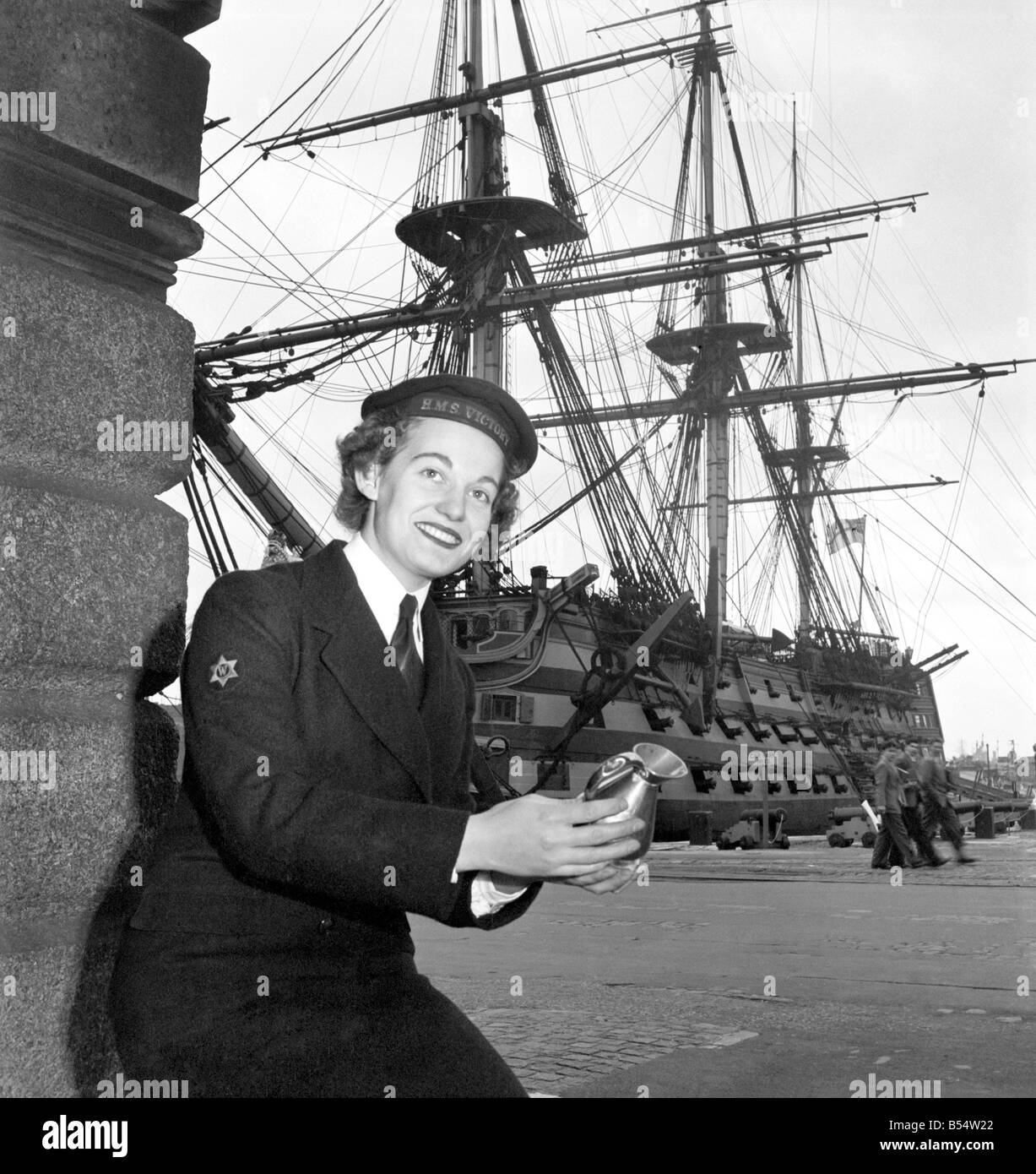 Royal Navy HMS Victory: WREN Margaret Mann 19 a winter in the navy, and Wren Joan Wallen age 20 of Radar Dept. They are intersted in a rum measure used aboard. The victory in Nelson days. October 1953 D615-002 Stock Photo
